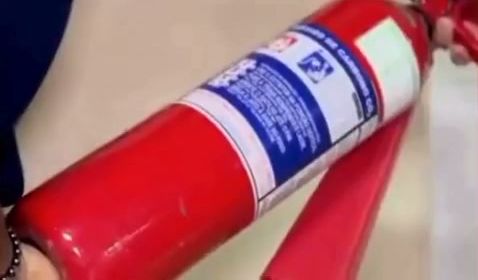 Técnico segurando um extintor vermelho durante a manutenção do equipamento